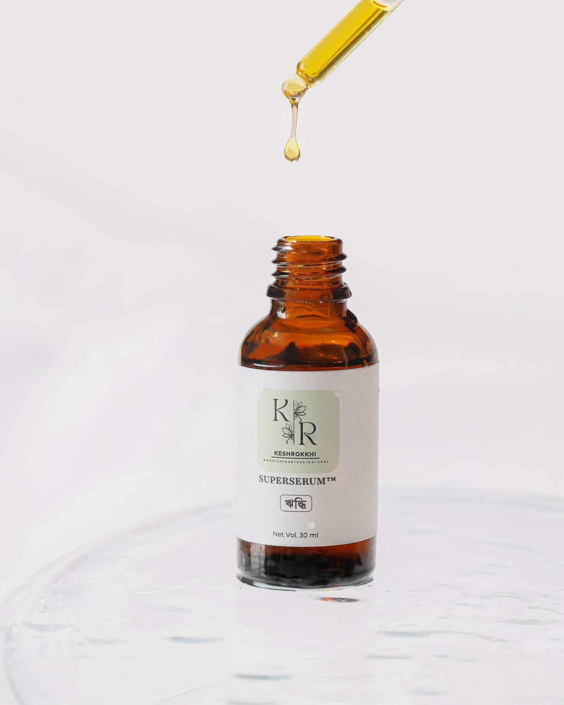 Dropper releasing Hridhhi SuperSerum™ oil into amber glass bottle — organic anti-hair fall solution made in Bangladesh with cold-pressed and essential oils.
