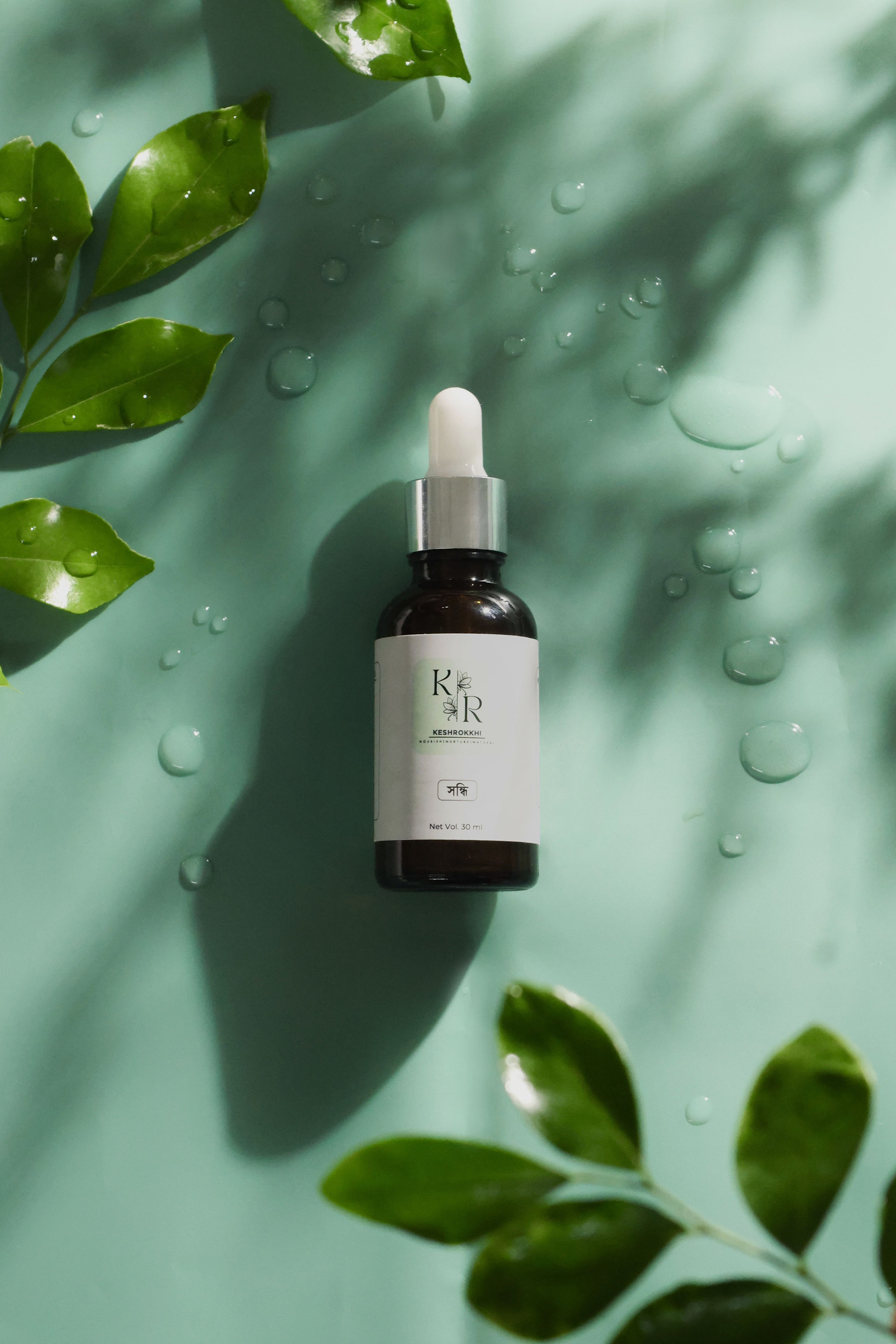 Keshrokkhi Shiondhi organic hair serum with nourishing oils on a green leaf backdrop- natural shine and repair oil for women, made in Dhaka, Bangladesh