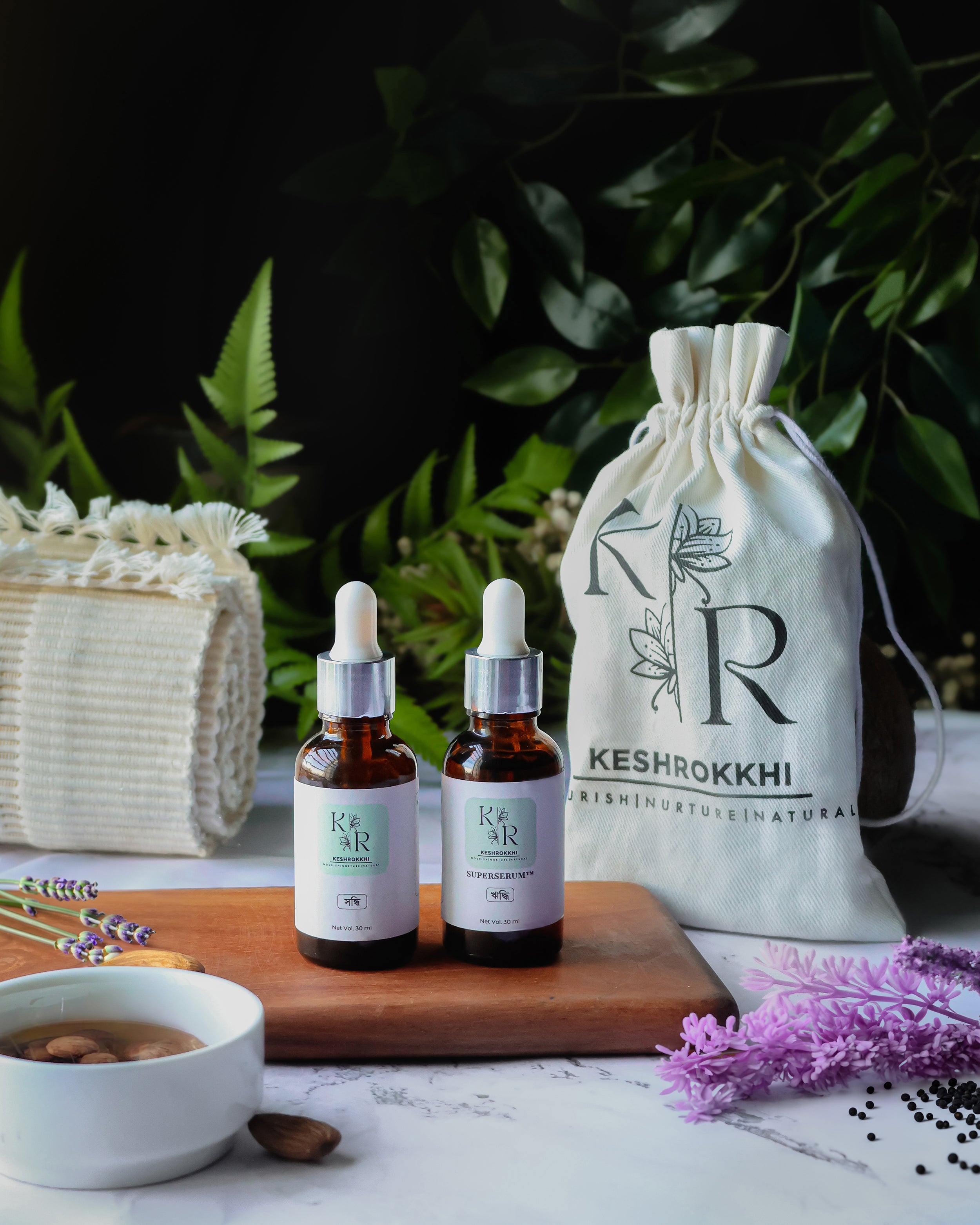 Keshrokkhi Hriddhi and Shondhi hair serums with drawstring pouch and towel on a wooden tray- natural hair care ritual from Bangladesh