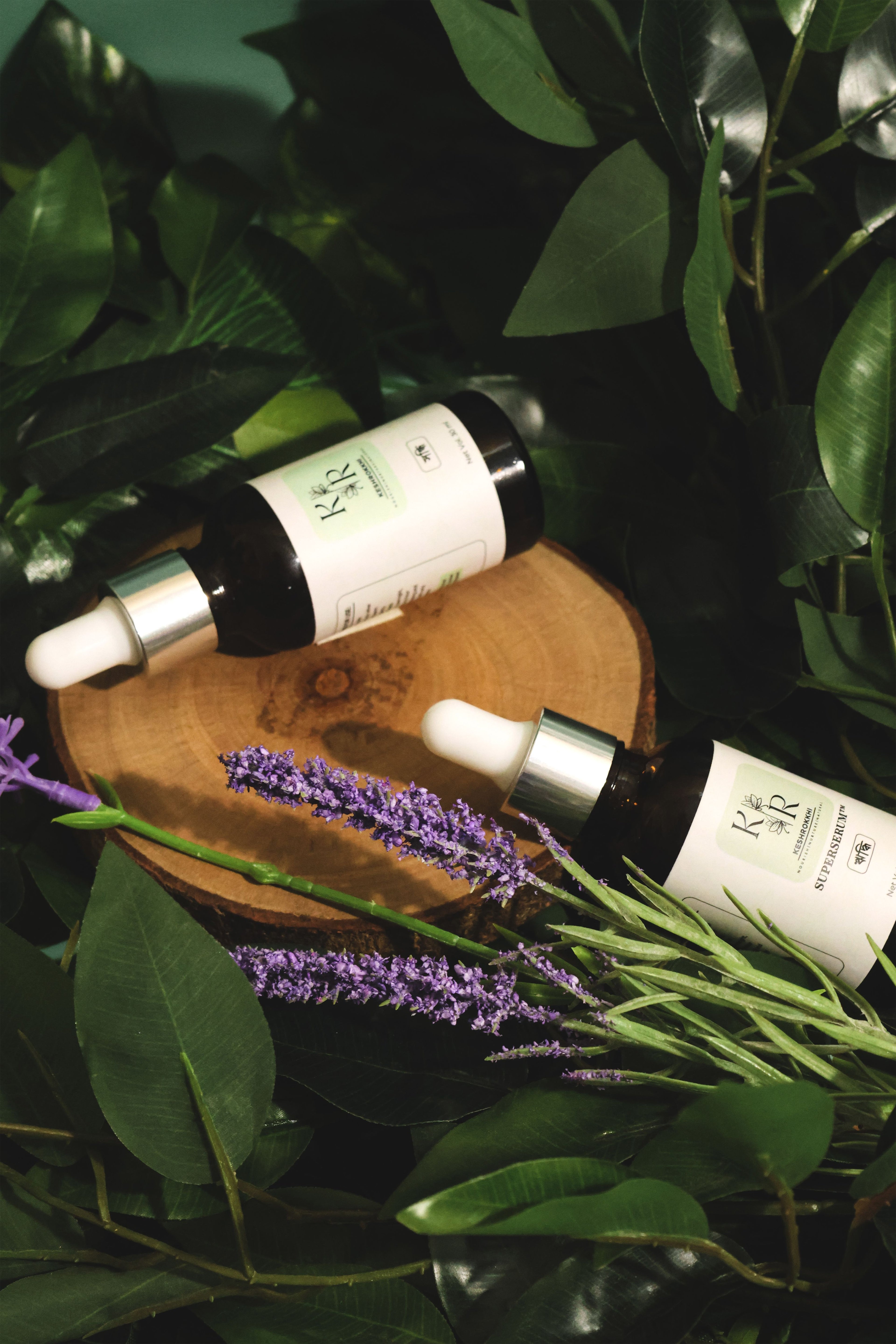 Hriddhi and Shondhi hair serums by KeshRokkhi plaved on a wooden platter with lavender and green leaves- natural organic hair care solution for hair fall and frizz, Dhaka, Bangladesh
