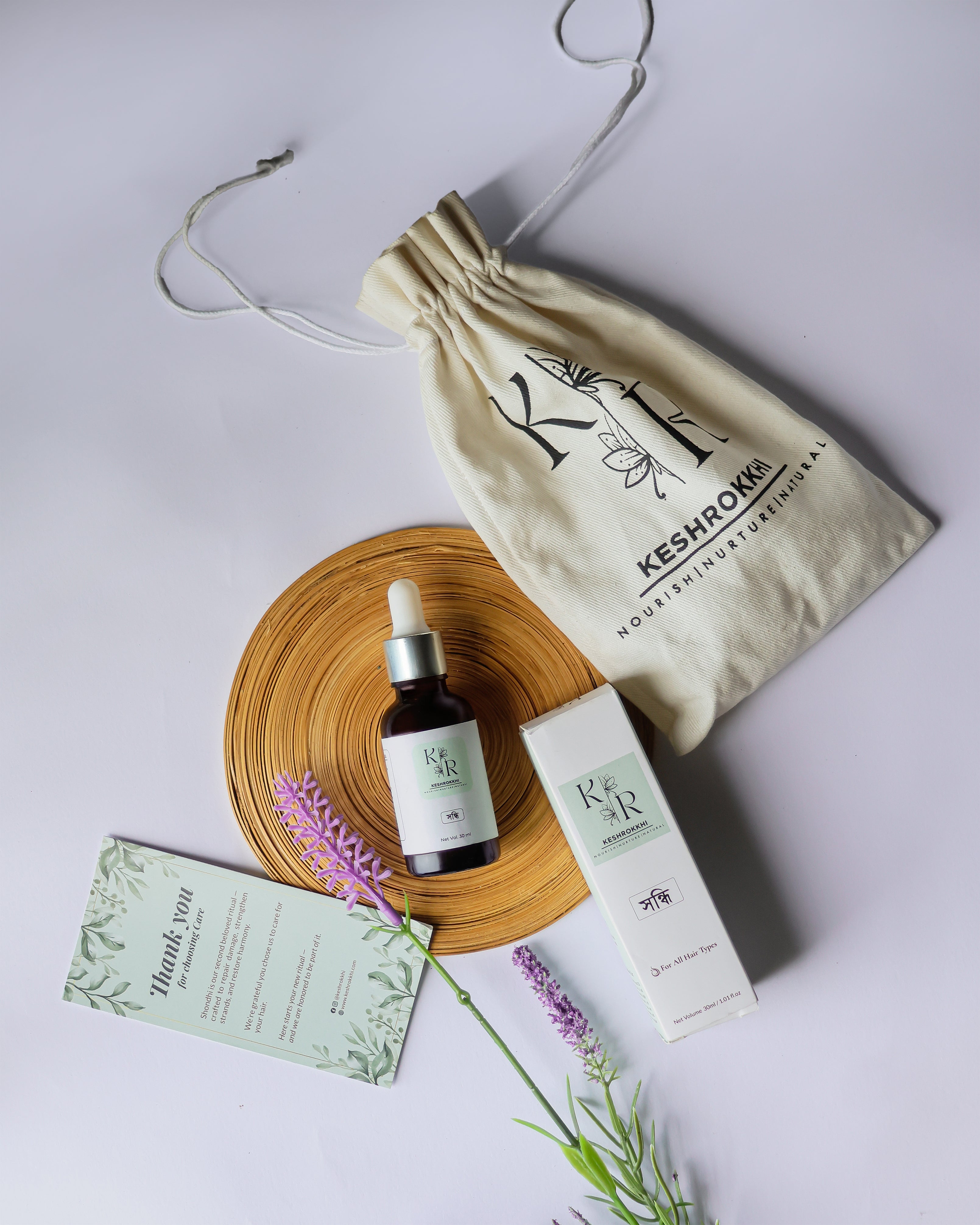 Keshrokkhi Shondhi hair repair oil with box, thank you card, and pouch- natural hair shine and nourishment solution with 6 oils, made in dhaka, bangladesh. Lavender flower used as props. 