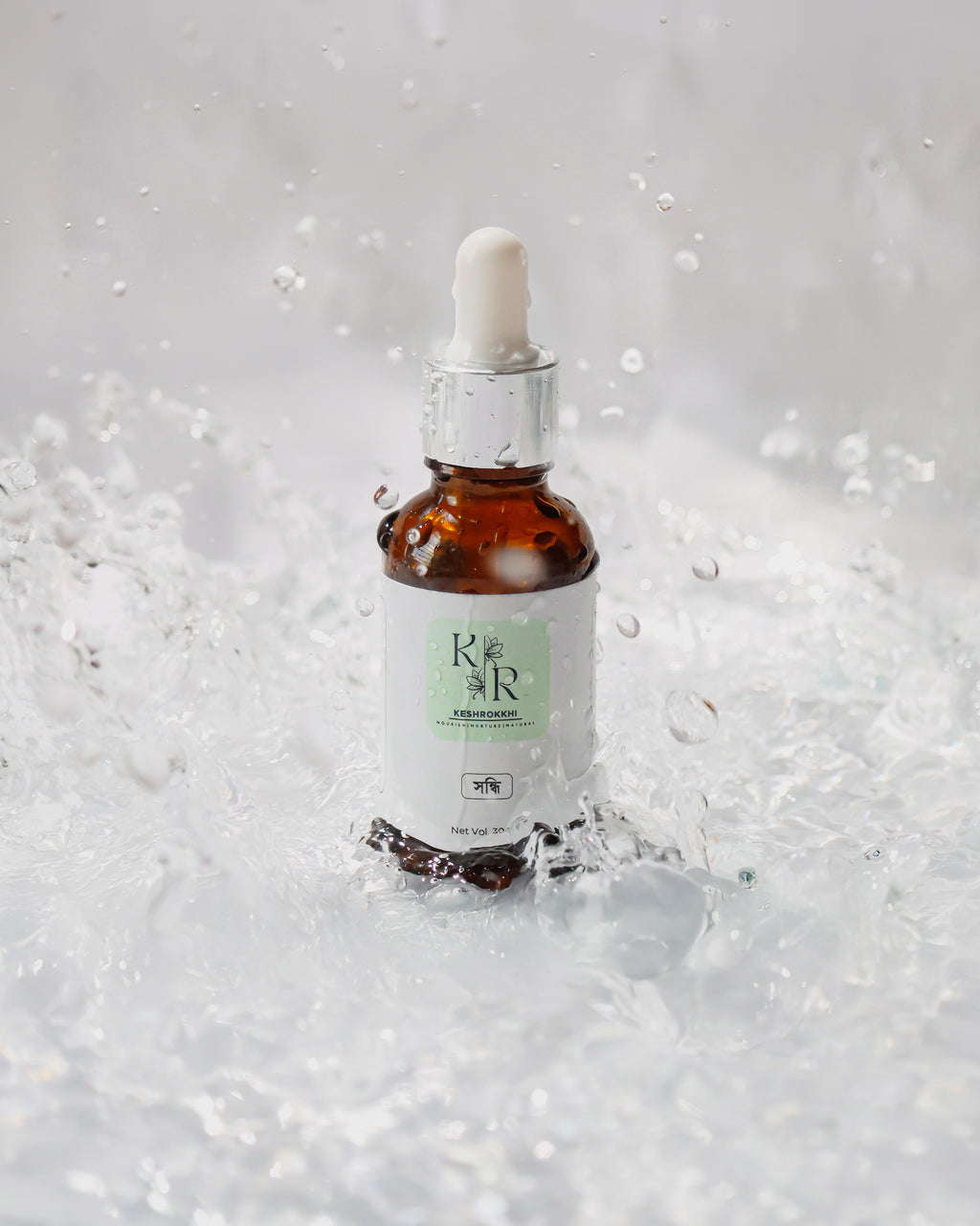 Shondhi Hair oil by Keshrokkhi captured mid-water splash for hydration and shine effect. 